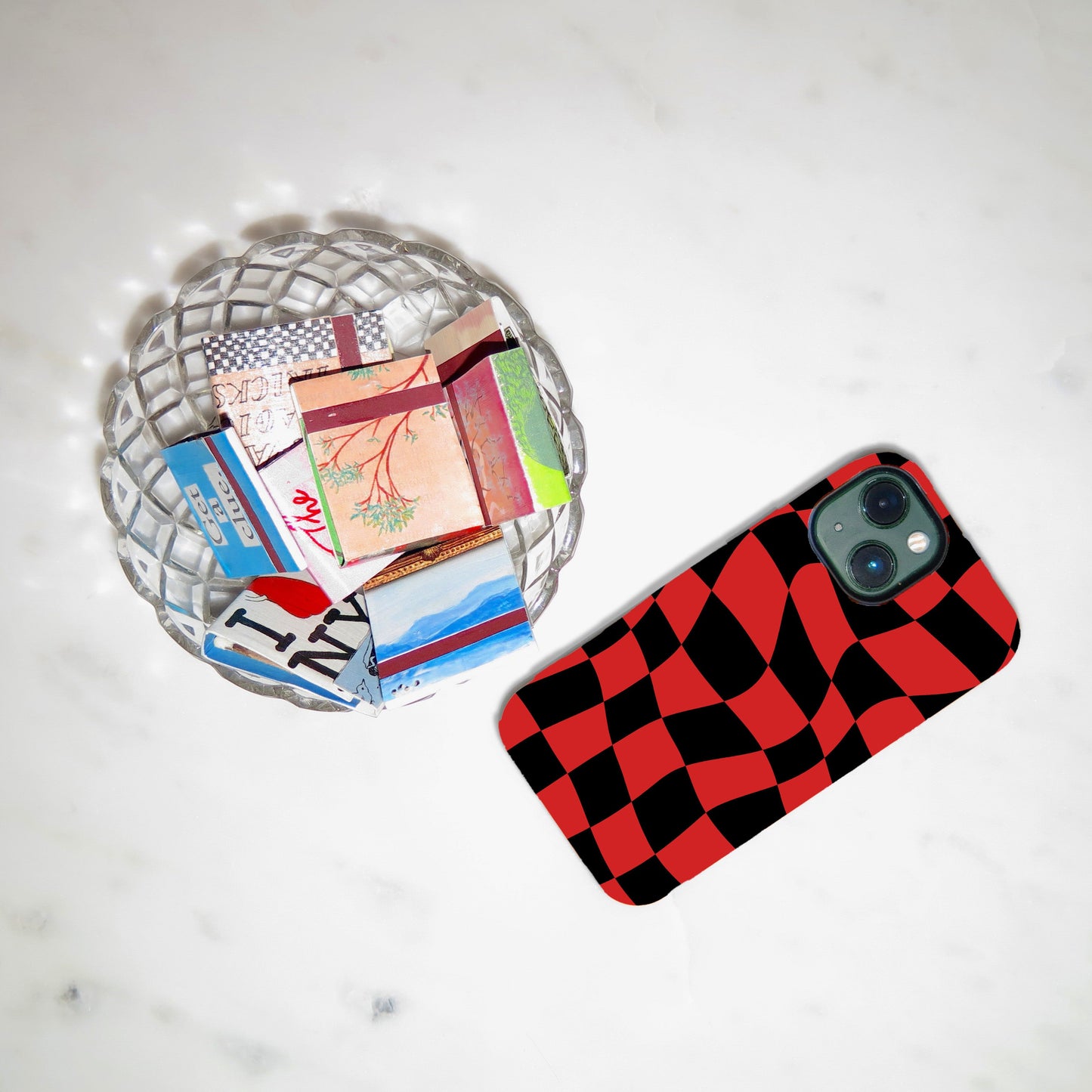 Phone case with red and black checkered pattern on a light gray surface